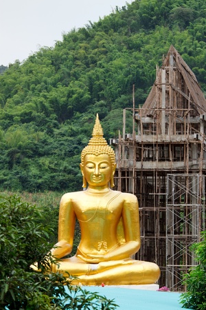 Buddha with the background of under-construction temple on mountainの写真素材