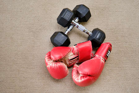Boxing gloves and dumbbells on a background of coarse fabricの写真素材