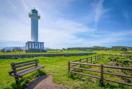 Cabo de Lastres lighthouse in Luces-Colunga, in Asturias (Spain), with a wooden bench in the foregroundの写真素材