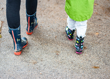 A girl with her mother walking down the street in wellies