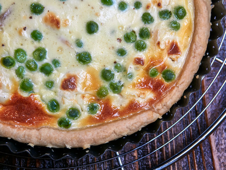 Smoked trout, goat cheese and peas quiche set on a cooling rack, top view