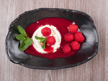 Vanilla bean pannacotta with raspberry coulis, fresh raspberries, and mint leavesの写真素材