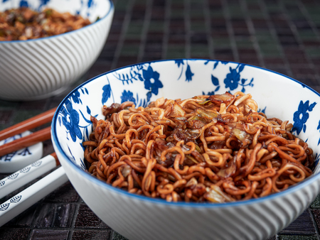 Soba Noodles with Yakisoba Sauce, prepared, served in white and blue bowl, with chopsticksの写真素材