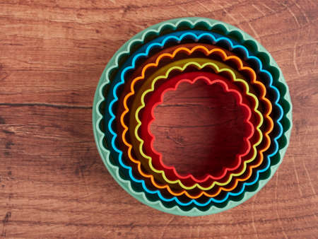 Colorful cookie cutters on wood background