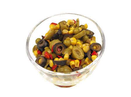 A bowl of steamed Mediterranean vegetables: corn, peas, peppers and green and black olives on a white backgroundの写真素材