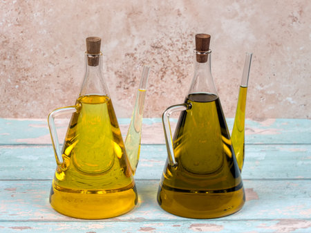 Two jugs of sunflower and olive oil, on bright blue wooden backgroundの写真素材