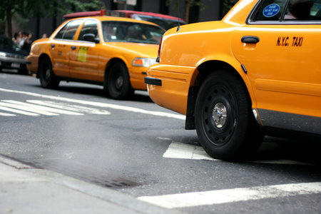 Taxi driving by a steaming manhole in New York City