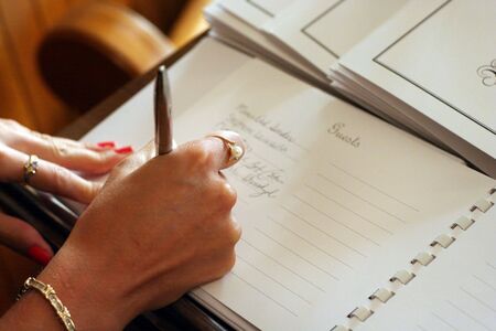 Womans hand signing a guest book with a penの写真素材