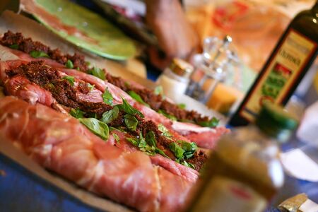 Preparing nice fresh piece of raw meat with basil, oil and tomato marinade. Narrow depth of field with brilliant colorsの写真素材