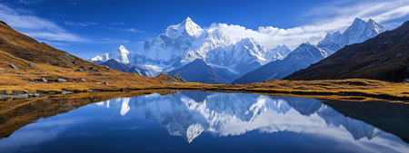 A majestic mountain range reflected in a still lake. The snow-capped peaks are illuminated by the...