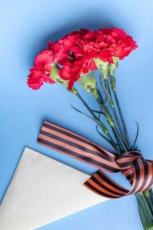 a bouquet of red carnations with a St. George ribbon and a triangular military envelope a field mail...