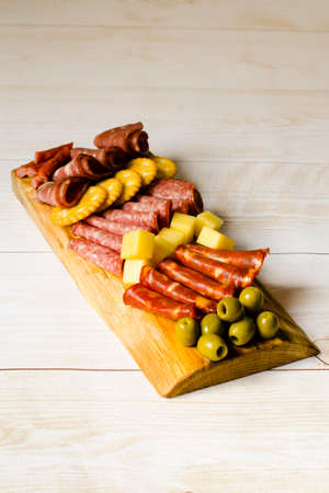 Charcuterie board. Board with snacks. cold cuts. Sausages, cheese, crackers and olives are...