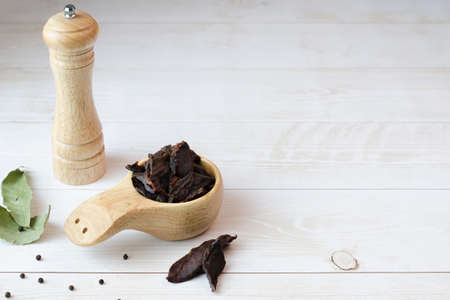 Jerky meat on a wooden background. Dried beef. rustic style. wooden dishes. copyspace. close up.