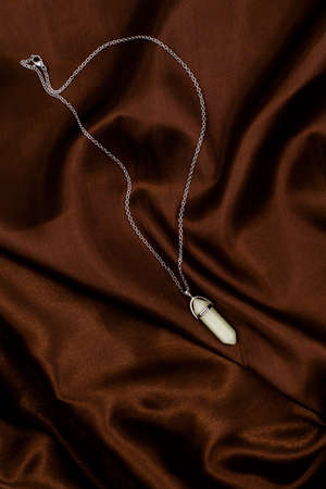 pendant made of natural jade stone on a background of satin brown fabricの写真素材