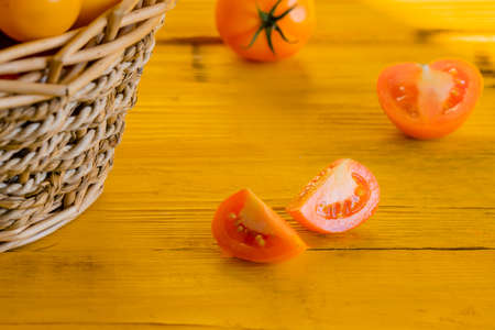A ripe juicy yellow tomato is cut lying on a wooden table, close-up of the yellow sub-roomの写真素材
