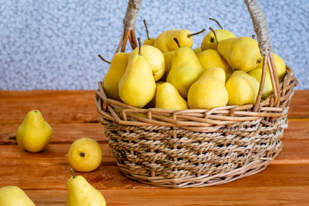 Basket with ripe juicy yellow pear sleep close-up wooden table, harvest pear in basketの写真素材