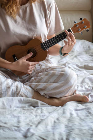 ukulele in women's hands, learning to play the ukulele close-up, Girl playing the ukulele, selective focus.の写真素材