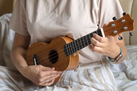 ukulele in women's hands, learning to play the ukulele close-up, Girl playing the ukulele, selective focus.の写真素材
