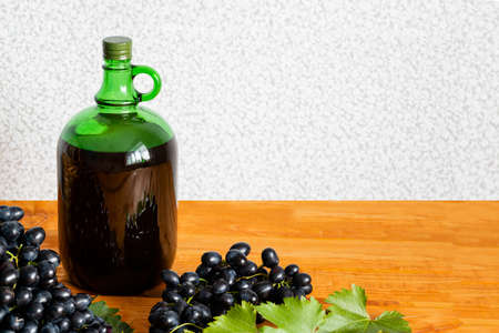 home winemaking. A huge brush of fresh juicy dark grapes against the background of a bottle of red wine close-up, Selective focus. copy spaceの写真素材