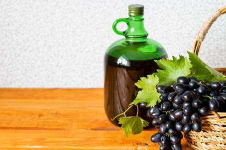 home winemaking. A huge brush of fresh juicy dark grapes against the background of a bottle of red wine close-up, Selective focus. copy spaceの写真素材