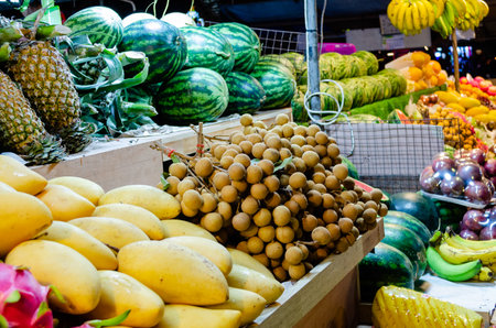 Exotic fresh juicy delicious Thai fruits at the night market in Pattaya Thailand: papaya, dragonfruit, passion fruit, mango, watermelons, bananas, pineapples, longan, lycheeの写真素材