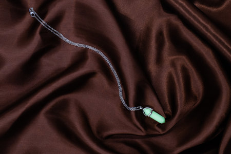 pendant made of natural jade stone on a background of satin brown fabricの写真素材