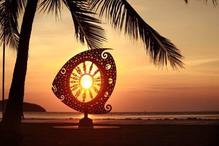 A sunset silhouette of the Mola Mola Sun Fish Sculpture at Saphan Hin in Phuket, Thailand, glowing...