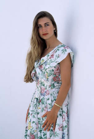 Young attractive woman in a summer dress, leaning against the wallの写真素材
