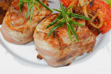 Grilled pork medallions with mushrooms, peppers, tomatoes on a plate