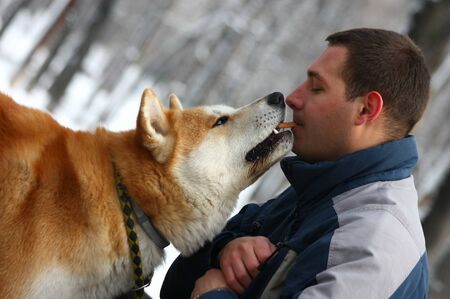 dog taking cracker from young man
