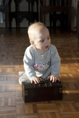 Cute baby girl trying to open the  boxの写真素材