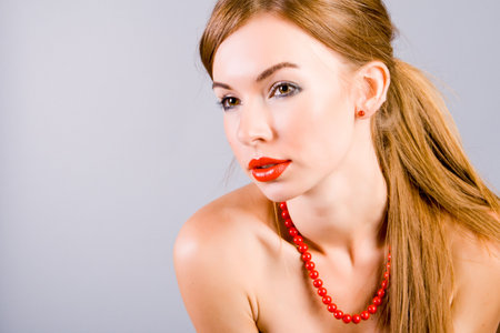 Portrait of the girl in red beads on gray backgroundの写真素材