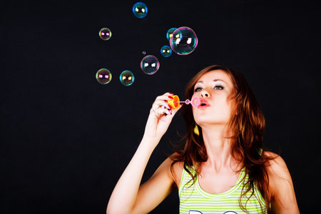 Picture of a young modest beautiful girl lets soap balls on back background
