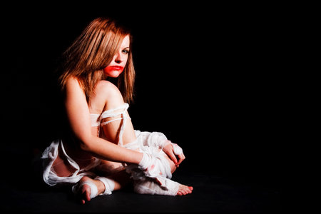 Picture of a girl in bandage white sited on floor on black backgroundの写真素材