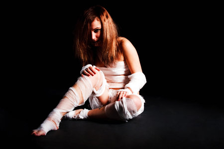 Picture of a girl in bandage white sited on floor on black backgroundの写真素材