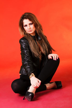 Picture of a attractive young girl in black jacket on orange backgroundの写真素材