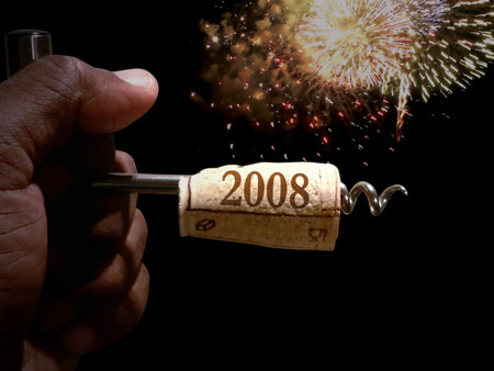 hand holding a cork screw just pulled from a bottle of wine to celebrate new years eve