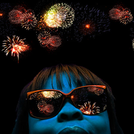 stylized facial portrait of a blue faced female with fireworks over head and reflecting off her...