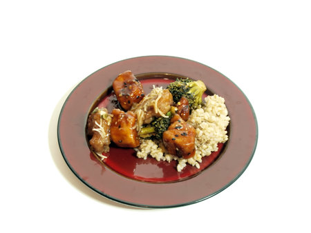 a meal of chinese food on a red plate consisting of pork, chicken, cheese, and brocolli, covered in a sauce on a white background with copy space.の写真素材