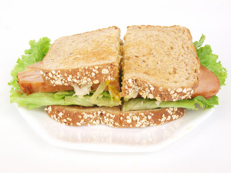 a sliced turkey sandwich with lettuce, tomato, onion, and mustard on a white background.の写真素材