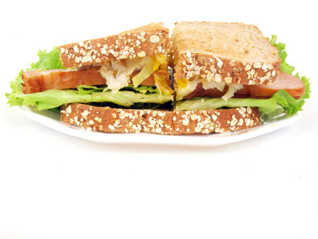 a sliced turkey sandwich with lettuce, tomato, onion, and mustard on a white background.の写真素材