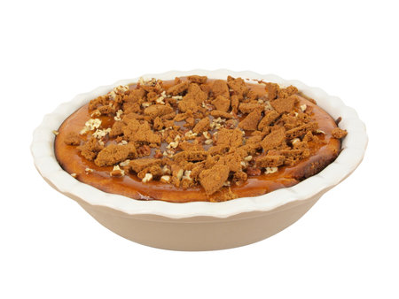 isolated photo of a homemade pumpkin and caramel cheesecake topped with walnuts and crushed ginger bread cookiesの写真素材