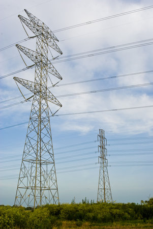 large power line towers in a green field against a blue skyの写真素材