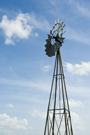 an old windmill against a bright blue sky with scattered cloudsの写真素材