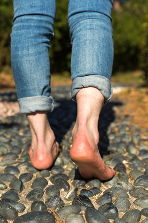 A woman doing acupressure on her bare feet for healthの写真素材