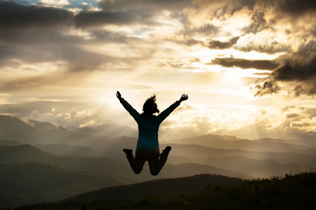 Silhouette of a freedom young jumping woman on the mountain Carpathiansの写真素材