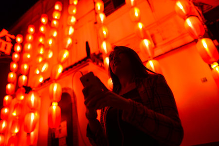 Chinese teenager with cell phone near chinese new year lanternsの写真素材