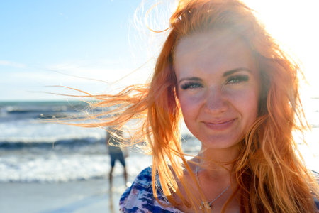 close up portrait of beauty young woman with long red hairs, agains sea coast backgroundの写真素材