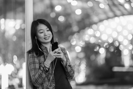 Close up portrait of woman listening music agains blured night city background