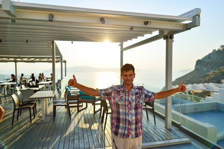 SANTORINI, GREECE - AUGUST 07, 2015: man posing agains open air restaurant on Santorini island. The traditional architecture of Santorini is similar to that of the other Cyclades, with low-lying cubical housesのeditorial素材